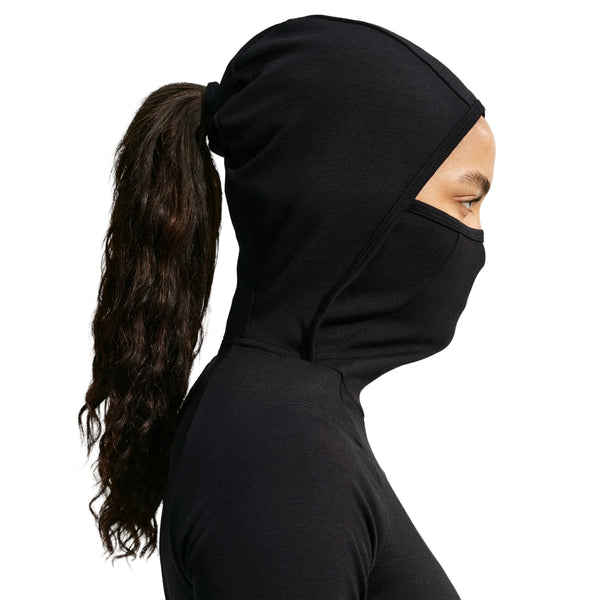 En person set i profil iført en sort Wool Running Mid-Layer Top, Dame, sort/sort/sort hættetrøje med integreret ansigtsdækning.