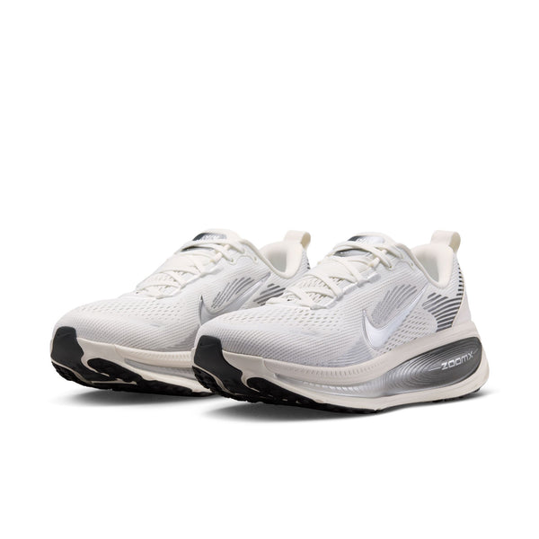 Et par Nike Vomero 18 løbesko til kvinder i farvekombinationen Summit White/Metallic Silver-Sail, med en åndbar overdel i mesh med sorte og grå detaljer, hvide snørebånd og sorte såler. Det karakteristiske Nike Swoosh-logo og ZoomX-mærket pryder siden af hver sko og sikrer maksimal dæmpning for øget komfort. Disse løbesko er inspireret af innovativt design og er perfekte til kvinder, der søger både stil og ydeevne.