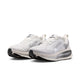 Et par Nike Vomero 18 løbesko til kvinder i farvekombinationen Summit White/Metallic Silver-Sail, med en åndbar overdel i mesh med sorte og grå detaljer, hvide snørebånd og sorte såler. Det karakteristiske Nike Swoosh-logo og ZoomX-mærket pryder siden af hver sko og sikrer maksimal dæmpning for øget komfort. Disse løbesko er inspireret af innovativt design og er perfekte til kvinder, der søger både stil og ydeevne.