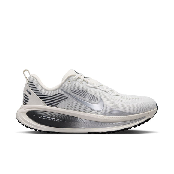 En Nike Vomero 18-løbesko til kvinder i farvekombinationen Summit White/Metallic Silver-Sail, med et metallisk sølvfarvet Nike-swoosh, sorte og grå detaljer på hælen samt »ZoomX«-logoet på den sorte mellemsål. Skoen giver maksimal dæmpning takket være den polstrede overdel i mesh og den slidstærke ydersål i gummi.