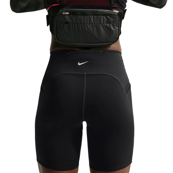 Der ses en person fra taljen til midt på låret iført Nike High-Waisted 7" løbeshorts med lommer i sort/reflekterende sølv og en sort bæltetaske. Personen har armene løftet, hvilket delvist afslører overkroppen.