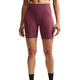 En person står foran en hvid baggrund iført Nike High-Waisted 7″ løbeshorts med lommer i farven Pink Smoke/Reflective Silver og sorte sokker. Armene hænger afslappet ned langs siden, og kun overkroppen og benene er synlige.