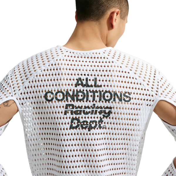 Man ser en person bagfra, der bærer Nike ACG Radical AirFlow NXT langærmet løbetrøje i farvekombinationen hvid/antracit, med teksten »ALL CONDITIONS Racing Dept.« trykt i sort på den øverste del af ryggen.