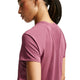 En person med flettet hår har Nike Dri-FIT Running Top, Dame, i farven Pink Smoke/Reflective Silver på, set bagfra og fra siden. Den kortærmede sportstrøje har mesh-detaljer på den øverste del af ryggen og er fremstillet af svedtransporterende stof for øget komfort. Baggrunden er ensfarvet hvid.