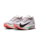 Et par Nike Zoom Fly 6 Dame-løbesko i farvekombinationen Lt Violet Ore/Baroque Brown-Sea Glass, med en lys lavendelblå overdel, sort Swoosh, koralrosa ydersål, hvid mellemsål og en lysegrøn detalje under fodbuen, vist side om side på en hvid baggrund. Disse innovative løbesko forener stil og ydeevne i ét elegant design med kulstoffiber.