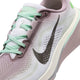 Et nærbillede af Nike Pegasus 42-løbeskoen til kvinder viser dens pastelfarvede farvekombination i Lt Violet Ore og Sea Glass med et markant sort Swoosh-logo, lysegrønne snørebånd og en overdel i mesh med farveovergang i lyserødt og hvidt. Denne stilfulde model er udstyret med avanceret Air Zoom-teknologi og en responsiv ReactX-mellemsål, der sikrer enestående komfort og ydeevne.