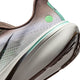 Nærbillede af hælen og sålen på Nike Pegasus 42 Herre i farvekombinationen Ironstone/Black-Sea Glass-Arctic Green, med en hvid og lysegrøn ReactX-skummellemsål i mellemsålen, brun mesh-overdel, synligt mønster på ydersålen og en grøn cirkulær detalje nær hælen.