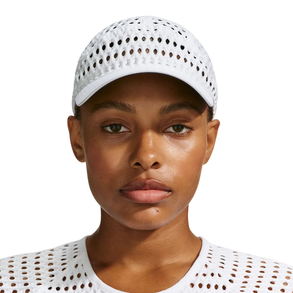 En person, der bærer en hvid Nike ACG Radical AirFlow Fly-kasket med et perforeret, åbent strikmønster.