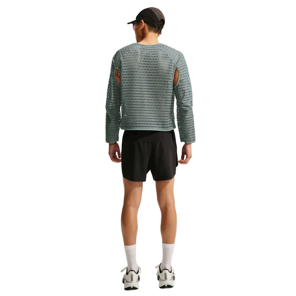 En person set bagfra, iført en grå Nike Stride Aero-FIT langærmet løbetrøje med udskæringer ved ærmegabene, sorte shorts, hvide sokker og løbesko.