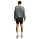 En person set bagfra, iført en grå Nike Stride Aero-FIT langærmet løbetrøje med udskæringer ved ærmegabene, sorte shorts, hvide sokker og løbesko.