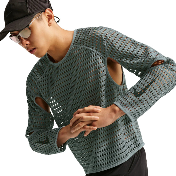 En person iført en grå Nike Stride Aero-FIT langærmet løbetrøje med udskæringer ved albuerne, en baseballkasket og solbriller.