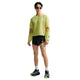En mand har en limegrøn, langærmet Nike Stride Aero-FIT langærmet løbetrøje, Herre, Lt Lemon Twist/Black med udskæringer ved skuldrene på, sammen med sorte løbeshorts og sportssko.