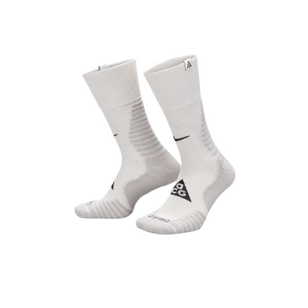 Nike ACG Crew Socks, unisex i Summit White/Lt Smoke Grey og fås i S, M, L, har en sort Swoosh, trekantet ACG-logo, ribkanter og er vist opretstående på en almindelig hvid baggrund.
