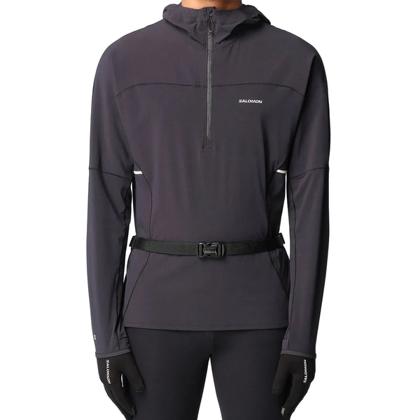 En person iført en sort Salomon-sportjakke med hætte og diskret logo, sorte handsker samt Salomon Active Belt 3D Bottle (unisex, sort) med letvægtsflaske står foran en ensfarvet lys baggrund.