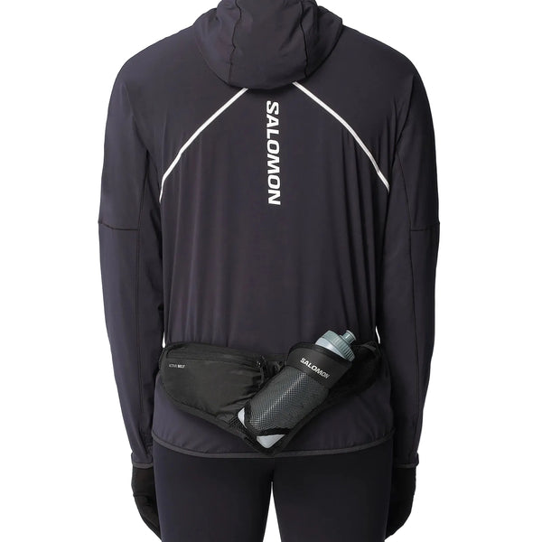 En person, set bagfra, er iført en sort Salomon-jakke med hætte, sorte handsker, leggings og et Salomon Active Belt 3D Bottle (unisex, sort) med en letvægtsflaske.