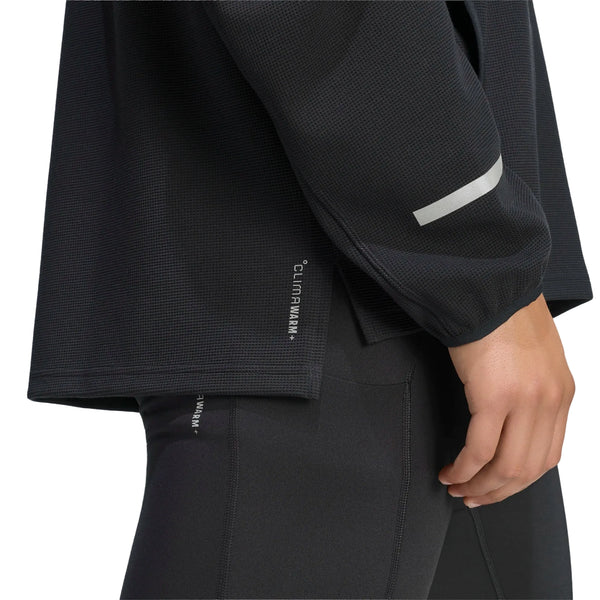 Nærbillede af en sort Adi365 Climawarm+ løbetrøje med rund hals, herre, med en reflekterende stribe på ærmet og teksten CLIMAWARM+ trykt på sidekanten.