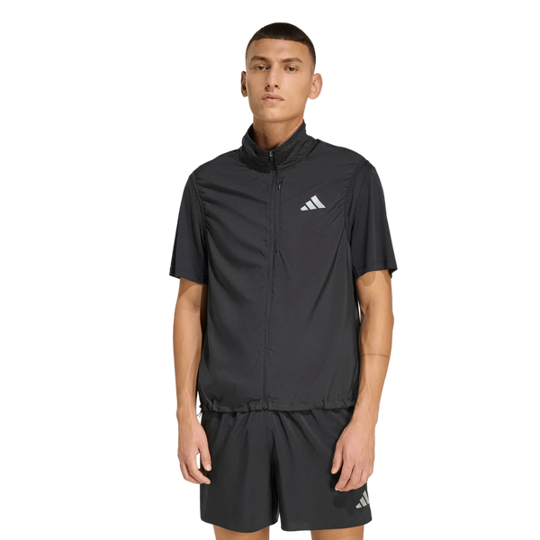 En mand står med ansigtet vendt fremad iført Adidas Adi365 Running Essentials Vest, Herre, i sort og tilhørende sorte shorts med hvide Adidas-logoer, set på en ensfarvet hvid baggrund. Dette sporty herreoutfit fra Adidas er perfekt til enhver sportslig lejlighed.