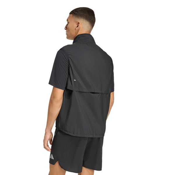 En mand står med ryggen til kameraet, klædt i et sportsoutfit bestående af sorte shorts og Adidas Adi365 Running Essentials-vesten, Herre, Sort. Den elegante vest har diskret Adidas-logo og er fotograferet foran en ensfarvet hvid baggrund.
