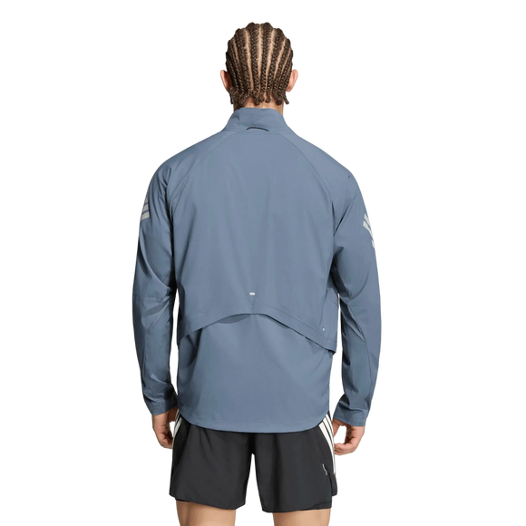 En person med flettet hår, set bagfra, er iført en lyseblå Adidas Adi365 Running Iconic-jakke (herre) i farvekombinationen Onix/Refsil samt sorte shorts. Løbejakken til herre har en ventilationsklap på ryggen og reflekterende detaljer på ærmerne. Baggrunden er ensfarvet hvid.