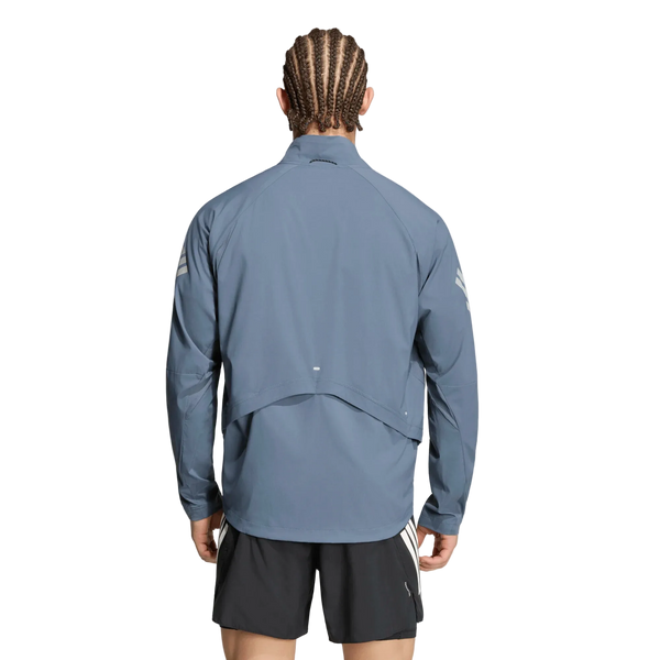 En person med flettet hår, set bagfra, er iført en lyseblå Adidas Adi365 Running Iconic-jakke (herre) i farvekombinationen Onix/Refsil samt sorte shorts. Løbejakken til herre har en ventilationsklap på ryggen og reflekterende detaljer på ærmerne. Baggrunden er ensfarvet hvid.