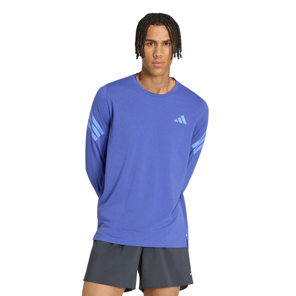 En mand iført en blå Adidas Adi365 Running Iconic langærmet trøje med tre striber på ærmerne og mørke shorts.