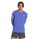 En mand iført en blå Adidas Adi365 Running Iconic langærmet trøje med tre striber på ærmerne og mørke shorts.