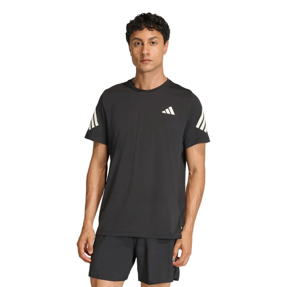 En mand med kort, mørkt hår har en sort Adidas Adi365 Running Iconic T-shirt til mænd på sig sammen med matchende sorte shorts. T-shirten har hvide striber på ærmerne og et lille hvidt adidas-logo på brystet. Han står med ansigtet vendt fremad foran en ensfarvet baggrund.