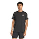 En mand med kort, mørkt hår har en sort Adidas Adi365 Running Iconic T-shirt til mænd på sig sammen med matchende sorte shorts. T-shirten har hvide striber på ærmerne og et lille hvidt adidas-logo på brystet. Han står med ansigtet vendt fremad foran en ensfarvet baggrund.