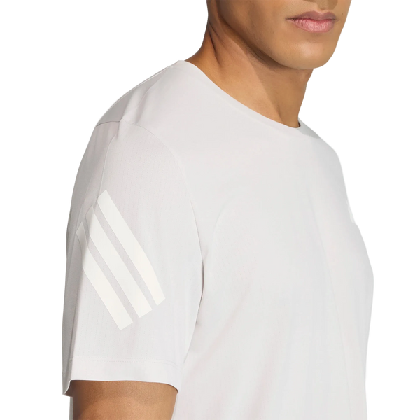 En person iført en Adidas Adi365 Running Iconic T-shirt til mænd i farven Greone/White med tre hvide striber på venstre ærme. Billedet er beskåret, så det kun viser overkroppen og en del af ansigtet.