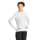 En person poserer iført Adidas Adi365 Running Winterized Long Sleeve træningsoverdel til kvinder i farven Greone, der har et diskret logo på brystet og er kombineret med sorte leggings. Med hænderne på hofterne og hovedet let vendt til siden fremviser vedkommende denne stilfulde langærmede træningsoverdel – perfekt til træning i køligt vejr.