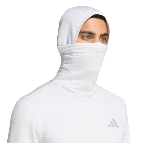 En person iført en grøn Adidas Adi365 Running Winterized langærmet herrebluse, hvor hætten er trukket op, og kraven dækker mund og næse, så kun øjnene og panden er synlige. Climawarm-stoffet holder personen varm i køligere vejr. Baggrunden er ensfarvet hvid.