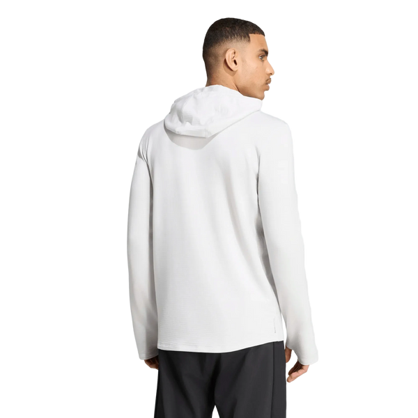 En mand iført Adidas Adi365 Running Winterized Long Sleeve til mænd i farven Greone, kombineret med sorte bukser, står med ryggen til og hovedet vendt til siden. Den ensfarvede hvide baggrund er perfekt til at fremhæve denne vinterløbetrøje til mænd.