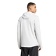 En mand iført Adidas Adi365 Running Winterized Long Sleeve til mænd i farven Greone, kombineret med sorte bukser, står med ryggen til og hovedet vendt til siden. Den ensfarvede hvide baggrund er perfekt til at fremhæve denne vinterløbetrøje til mænd.