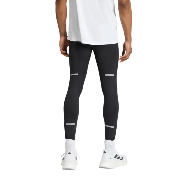 En person ses bagfra iført en hvid skjorte, Adidas Adi365 Tights M for men i sort med refleksstriber, hvide sokker og hvide sneakers mod en almindelig hvid baggrund.