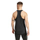 En muskuløs mand med kort hår og synlige tatoveringer bærer den sorte Adidas Adizero E Singlet (Herre) og sorte shorts, mens han står med ryggen til kameraet mod en hvid baggrund.