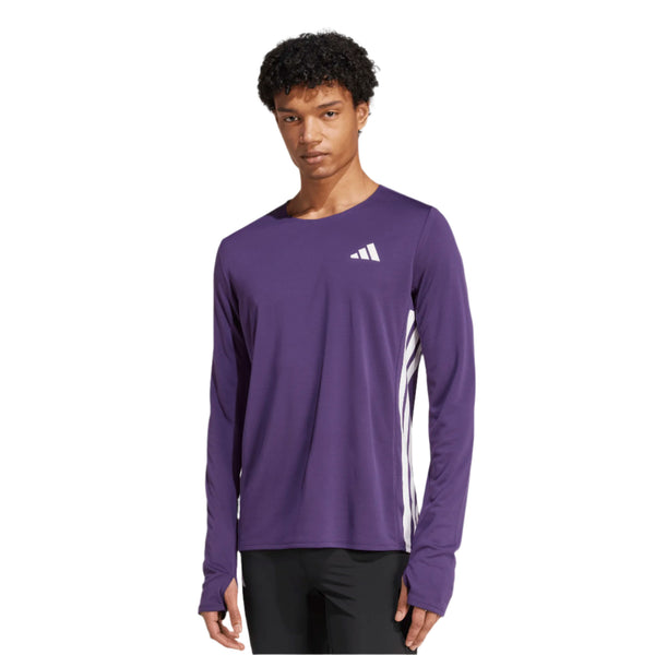 En mand er iført Adidas Adizero L Tee M i Aurplu, en langærmet lilla løbetop lavet af genbrugsmaterialer med et hvidt Adidas-logo på brystet, som står på en almindelig hvid baggrund.