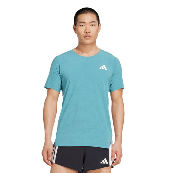En person står og kigger fremad iført en Adidas Adizero Running T-Shirt for herre i powder teal, fremstillet af 70% genbrugsmaterialer, med et hvidt adidas-logo, og sorte sportsshorts med hvide striber og et hvidt adidas-logo.