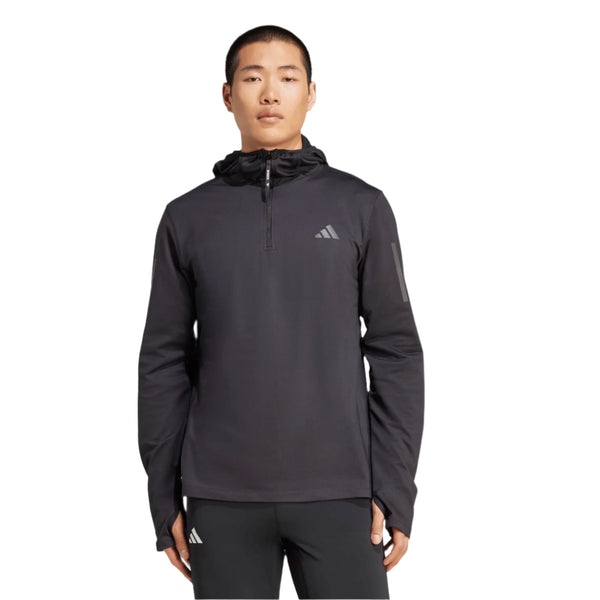 En person iført en Adidas Otr Bin Hz løbetrøje til mænd i sort med CLIMAWARM-teknologi, lynlås foran og et lille logo på brystet står på en almindelig hvid baggrund.