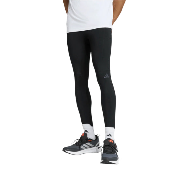 En person iført Adidas Otr Bin Tig løbetights, Herre, Black, hvide sokker og sorte løbesko med hvide såler står mod en almindelig hvid baggrund. Kun den nederste halvdel af kroppen er synlig.