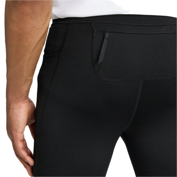 Nærbillede af en person iført Adidas Otr Bin Tig løbetights til herre i sort med CLIMAWARM-teknologi og lynlåslomme bagpå linningen. Personen står med en afslappet hånd ved siden.