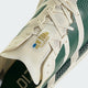 Nærbillede af en Adidas Adizero Adios Pro 5-løbesko i farverne Off White/Collegiate Green/Royal Blue med en cremefarvet overdel, grønne detaljer og en tunge med teksten New York Together samt et blåt 26,2-maratonmærke.