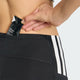 En person gør sig klar til løb ved at stikke en sort Maurten Gel 100 ned i baglommen på Adidas Adizero Shorts Tights, Dame, Sort.