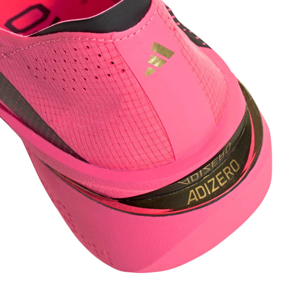 Nærbillede af hælen på Adidas Adizero Adios Pro 5 Dame-løbeskoen i farvekombinationen Soltur/Cblack/Lucred, med guld- og sorte detaljer samt synligt mærkelogo og ADIZERO-tekst på mellemsålen – ideel til maratonløb og udviklet som en konkurrencesko til eliten.