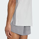 En person iført en Adidas Adizero Archive løbetrøje til mænd (Greone/Grethr) og lysegrå løbeshorts. Kun underkroppen, venstre arm og lårene er synlige på en ensfarvet baggrund.