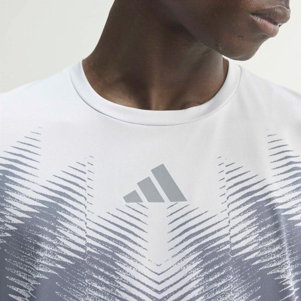 Nærbillede af en person, der bærer en hvid Adidas Adizero Aspyre Running Climacool-T-shirt med et gråt Adidas-logo og et abstrakt stribemønster, der fremhæver T-shirtens slanke design. Kun den nederste del af ansigtet, halsen og den øverste del af brystet er synlige på en ensfarvet, lys baggrund.