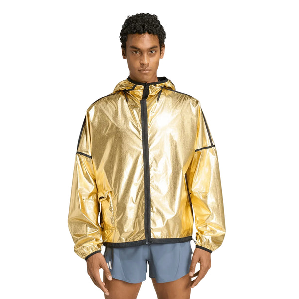 En person står med ansigtet vendt fremad iført en Adidas Adizero Running Blaze-jakke til mænd i sort og lyseblå shorts foran en ensfarvet hvid baggrund.