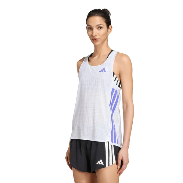 En person iført en Adidas Adizero løbetrøje til kvinder i farverne hvid/solpur og sorte sportsshorts med hvide striber står foran en ensfarvet hvid baggrund.