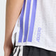Nærbillede af en person iført Adidas Adizero løbetrøje til kvinder i farven White/Solpur, kombineret med sorte shorts med hvide striber.