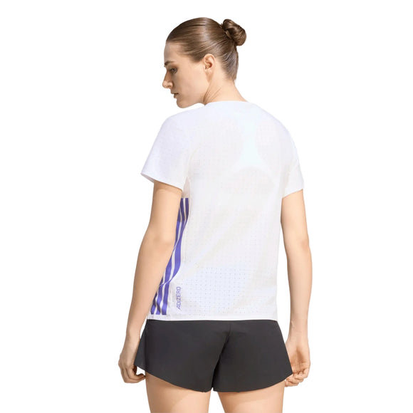 En person med brunt hår sat op i en knold står med ryggen til og har en Adidas Adizero løbetrøje (Dame, hvid/Solpur) på, kombineret med sorte shorts, foran en ensfarvet hvid baggrund.