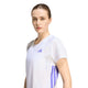 En brunhåret kvinde med håret sat op har en Adidas Adizero Running T-shirt, Dame, i farven White/Solpur på sig og står foran en ensfarvet hvid baggrund.